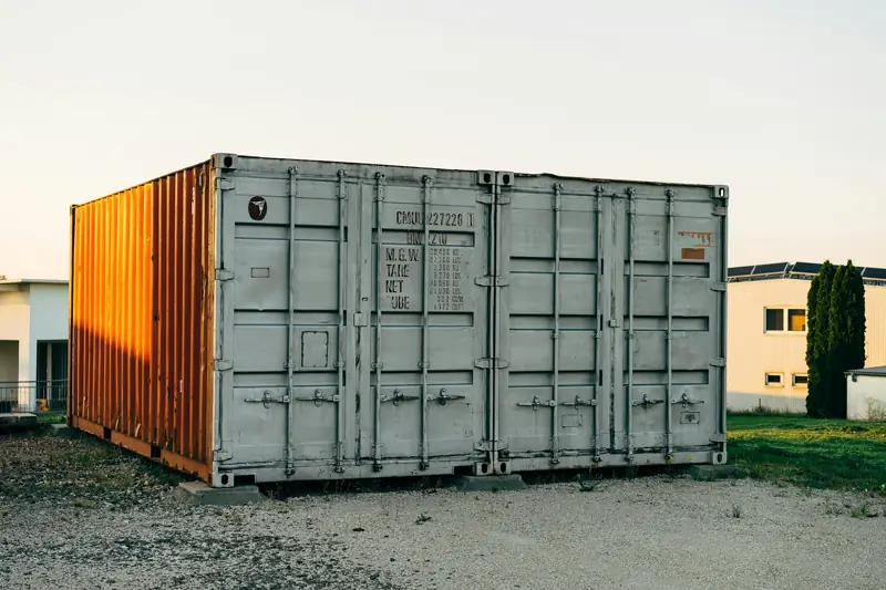 Used shipping container sitting on a gravel lot